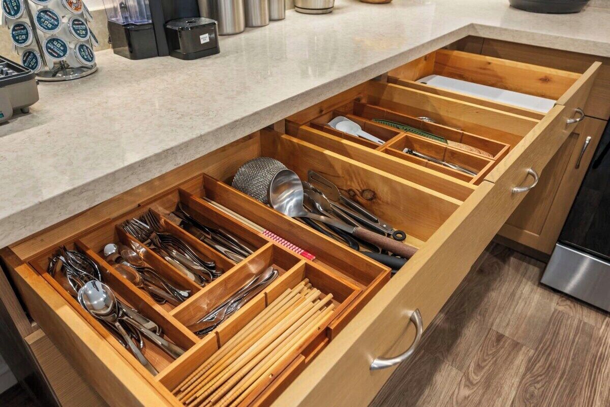 A kitchen with a wooden drawer organizer containing utensils.