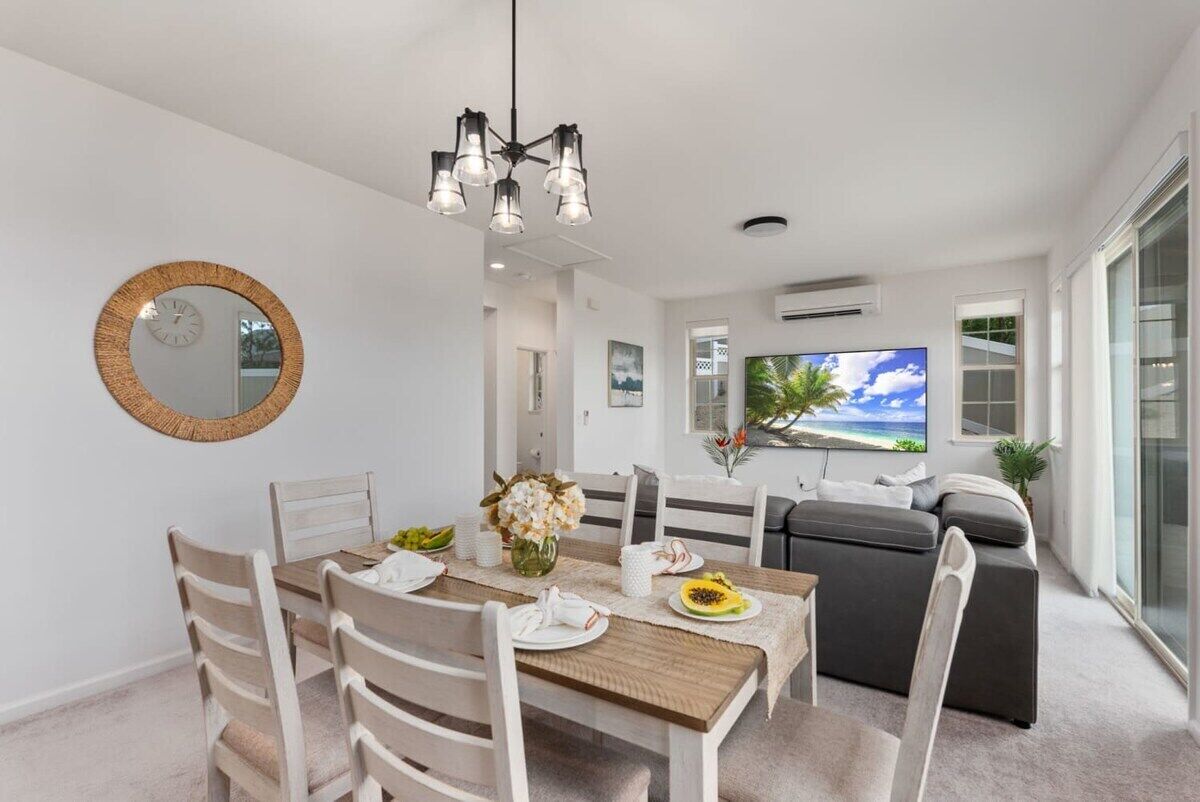 A modern dining area with a wooden table, white chairs, and a chandelier.