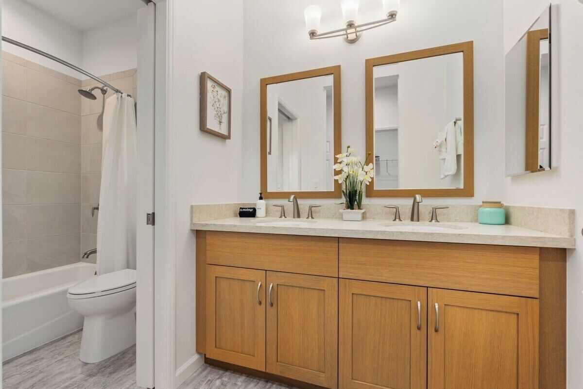 A modern bathroom with a shower, toilet, and double sink vanity with wooden cabinets.
