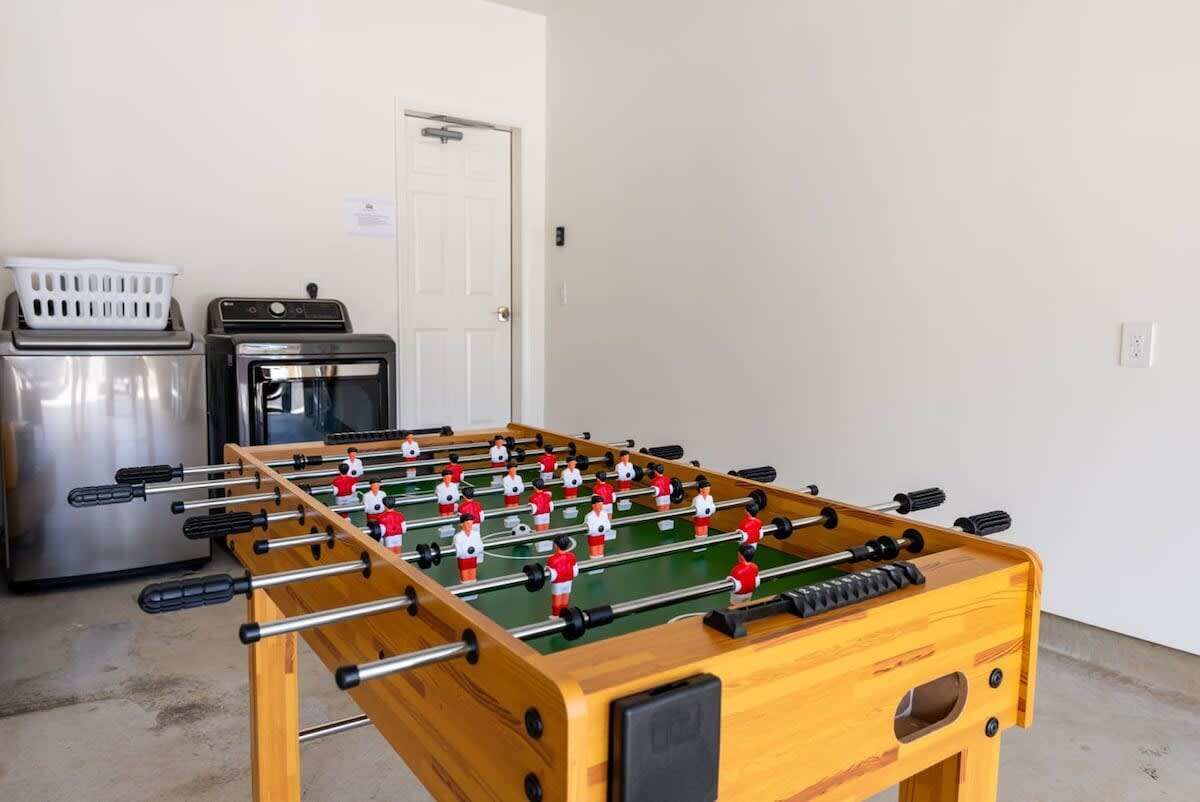 Une table de baby-foot dans une pièce avec un appareil en acier inoxydable et une porte blanche.