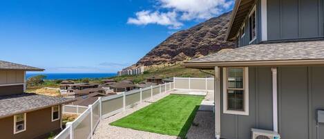A residential property with a well-maintained lawn, a gravel driveway, and a view of a mountainous landscape.