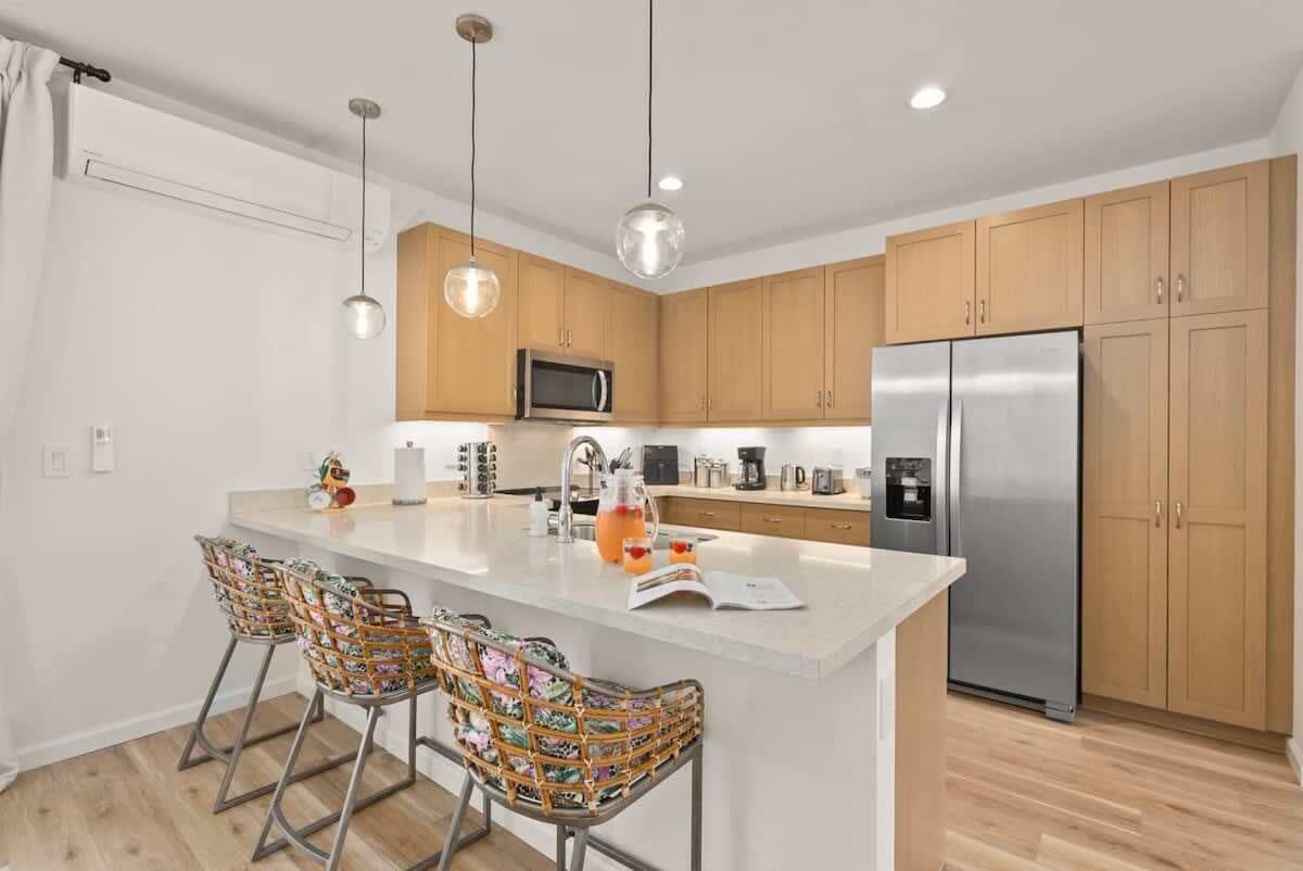 A modern kitchen with wooden cabinets, stainless steel appliances, and a central island with bar stools.