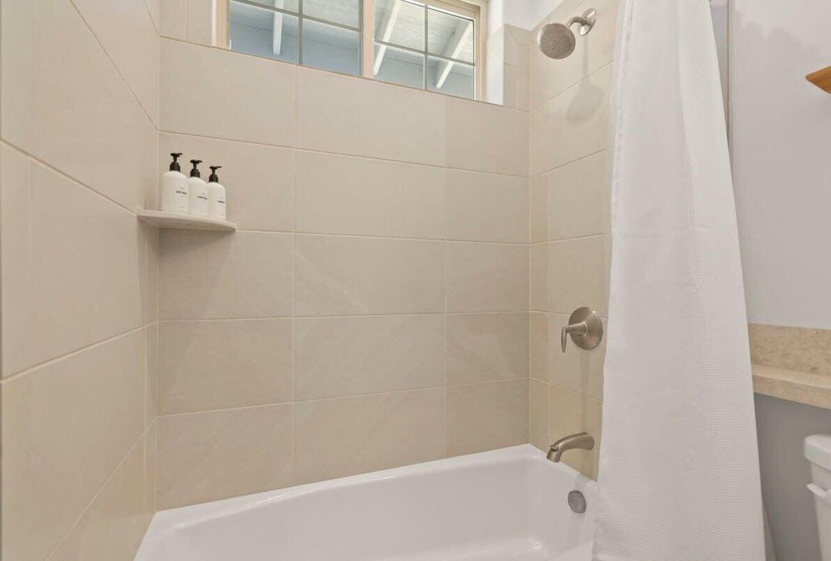 Ein Badezimmer mit einer Badewanne, einem Ablagefach für Toilettenartikel und einem Fenster über dem Ablagefach.