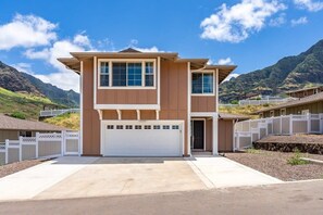 Ein zweistöckiges Haus mit Garage, weißem Zierzaun und einer Bergkulisse.
