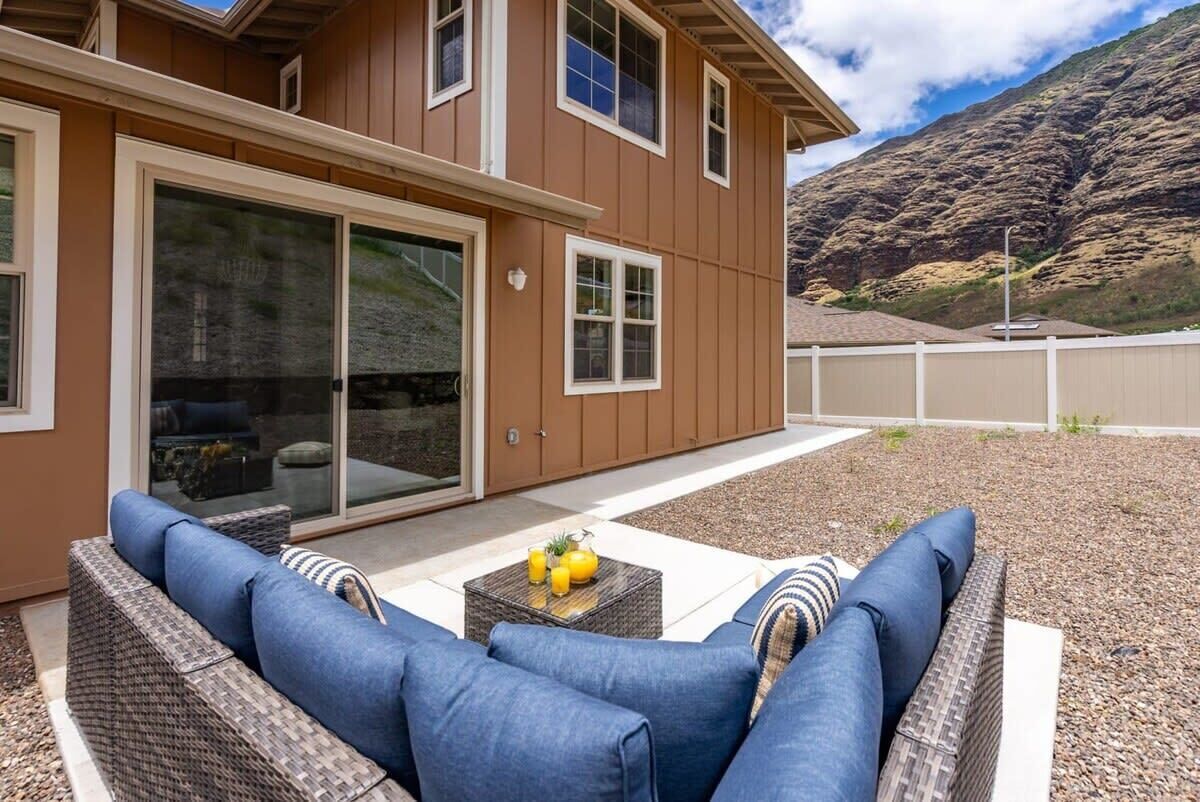 A modern house with a patio area featuring a wicker sofa and a small table with drinks.