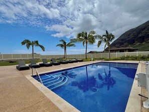Una piscina al aire libre, sombrillas, sillones reclinables de piscina