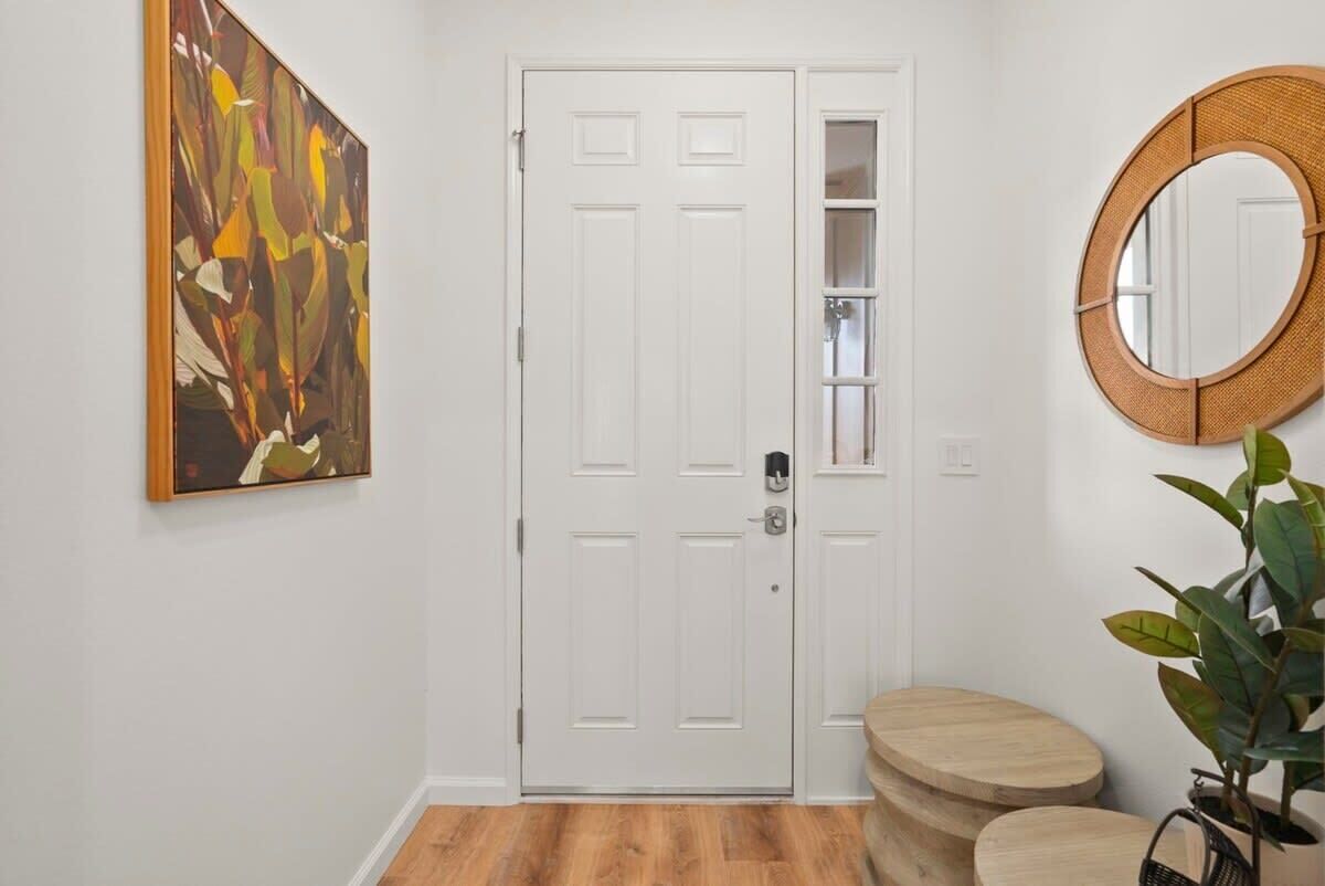 A hallway with a white door, a round mirror, and a wooden bench.