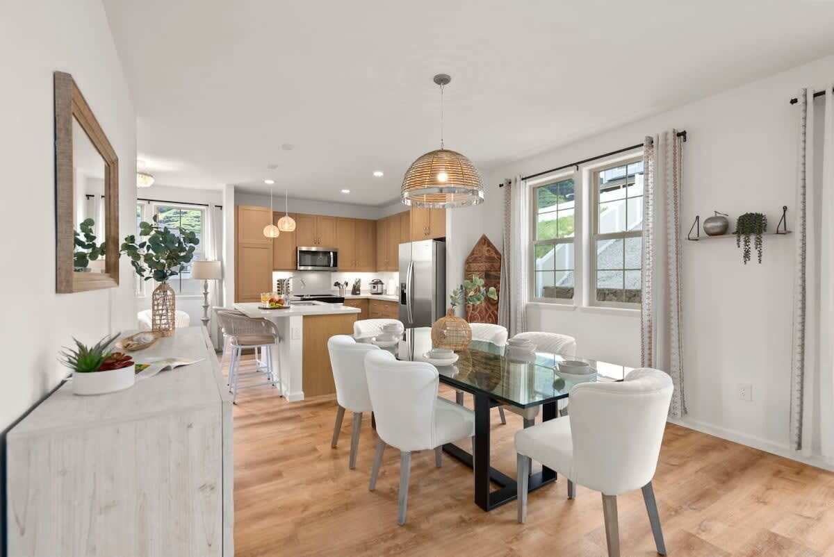 A modern kitchen with wooden cabinets, a central island, and white chairs.