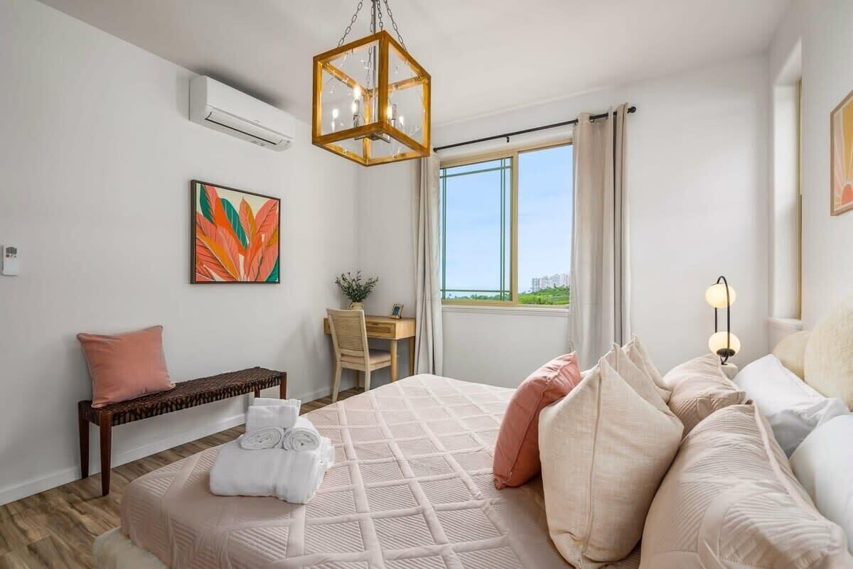 Quarto com uma cama grande, uma escrivaninha e janela com vista.
