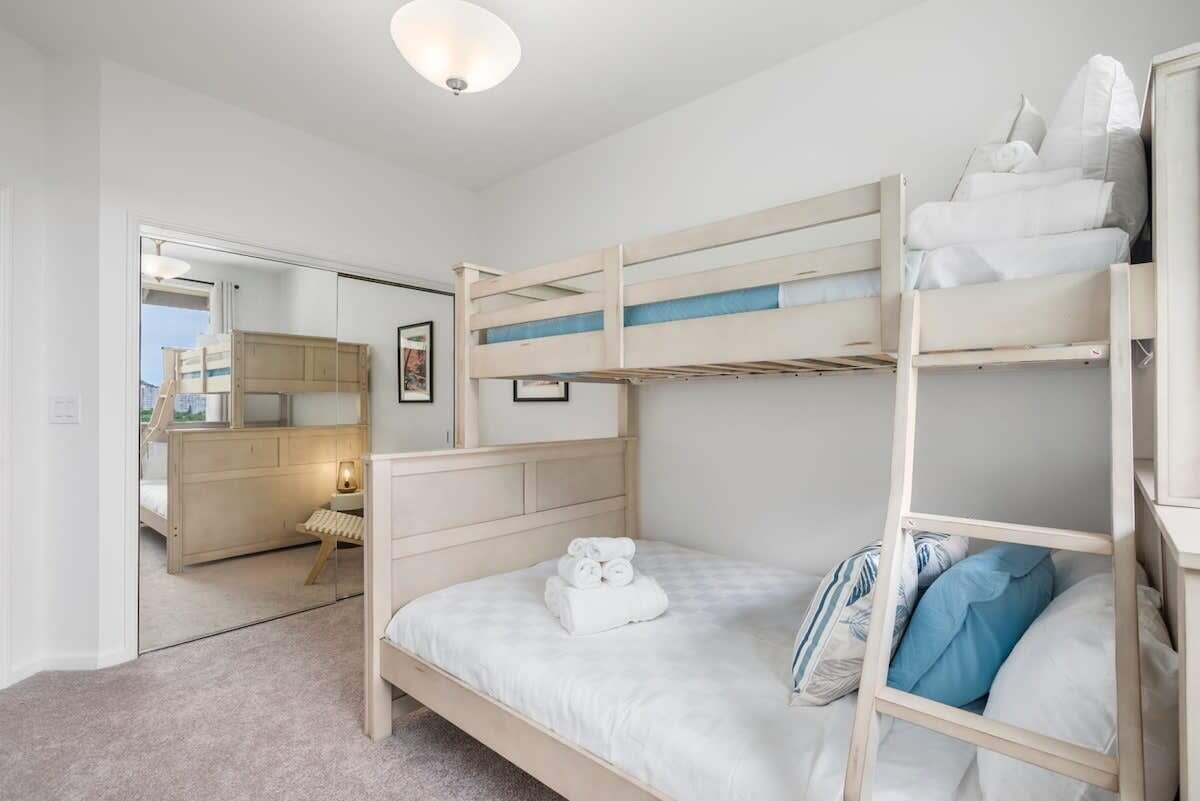 A bunk bed room with a mirror, a small desk, and a chair.