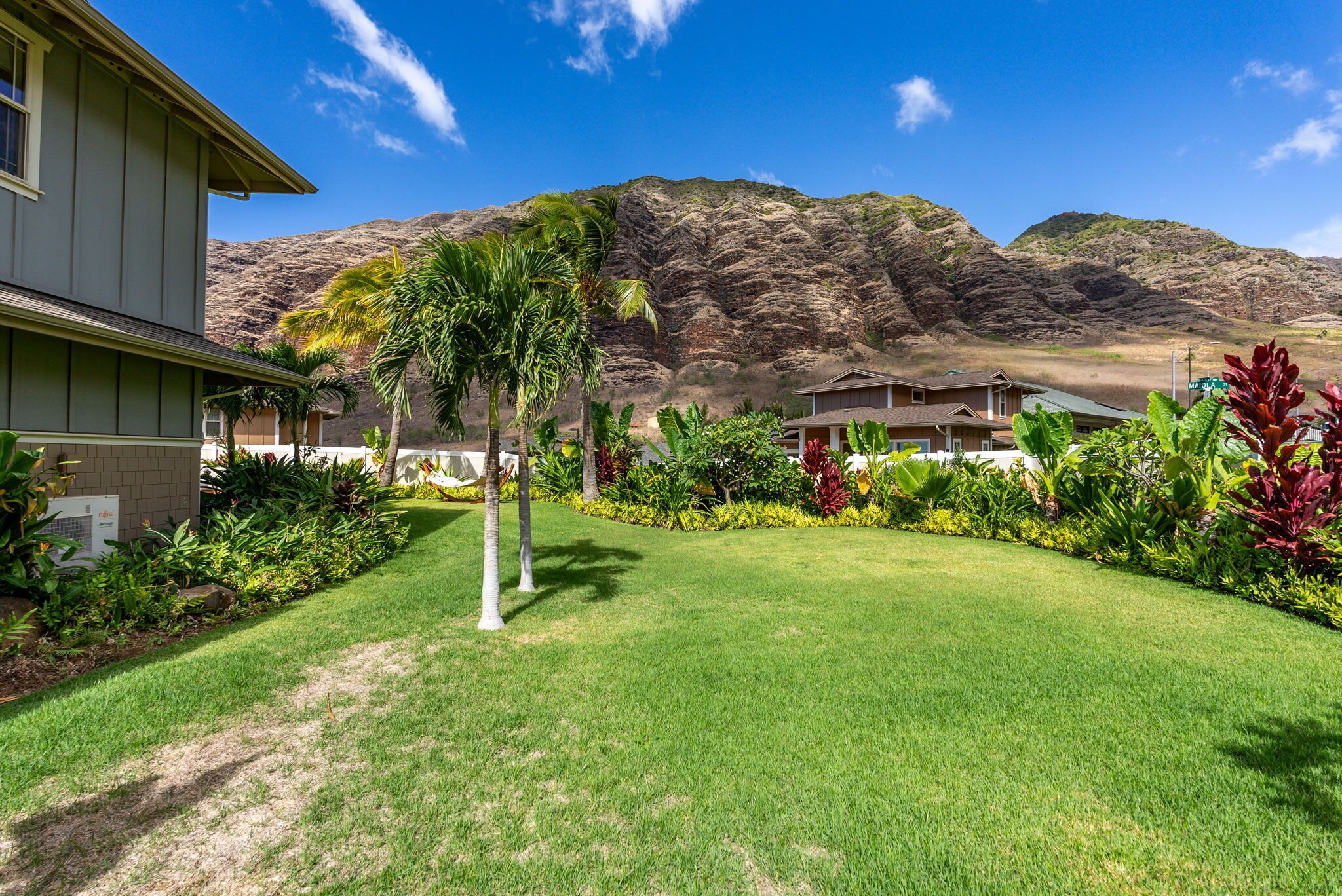 A hotel with a well-maintained lawn, palm trees, and a mountain backdrop.