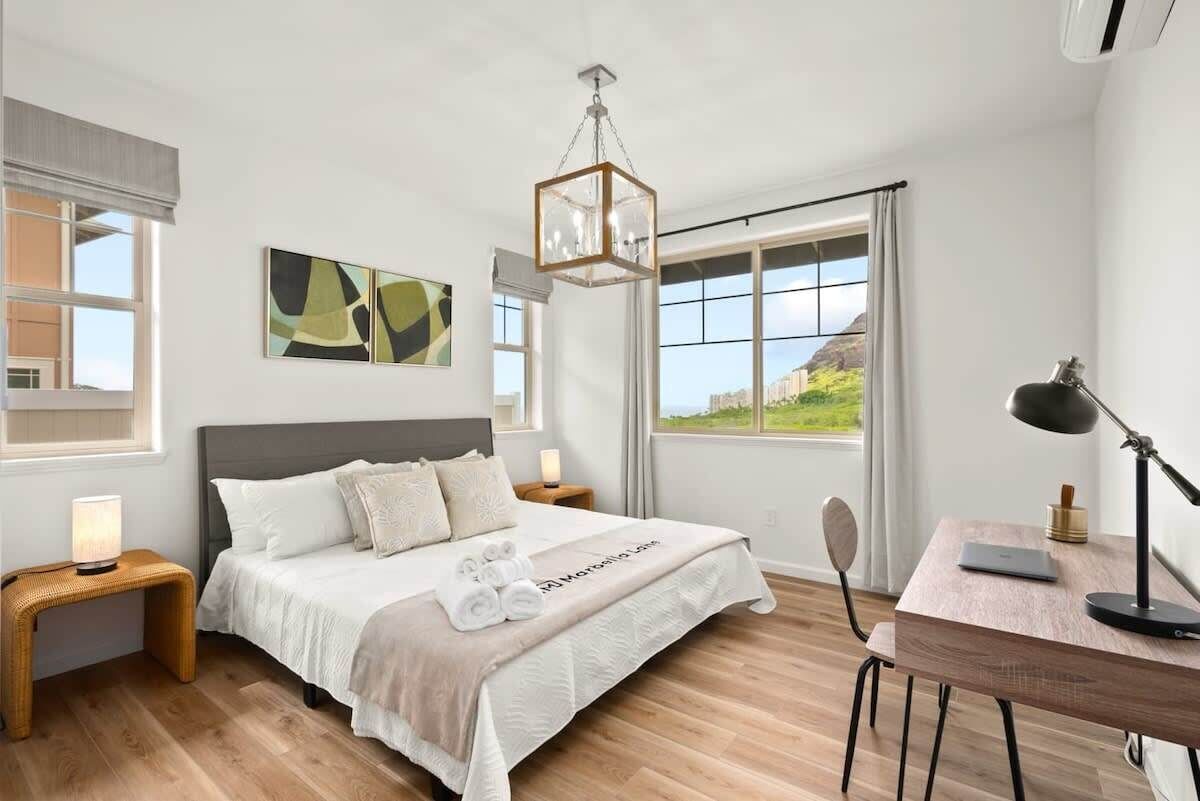 Un dormitorio moderno con una cama grande, un escritorio y vistas a un paisaje verde.