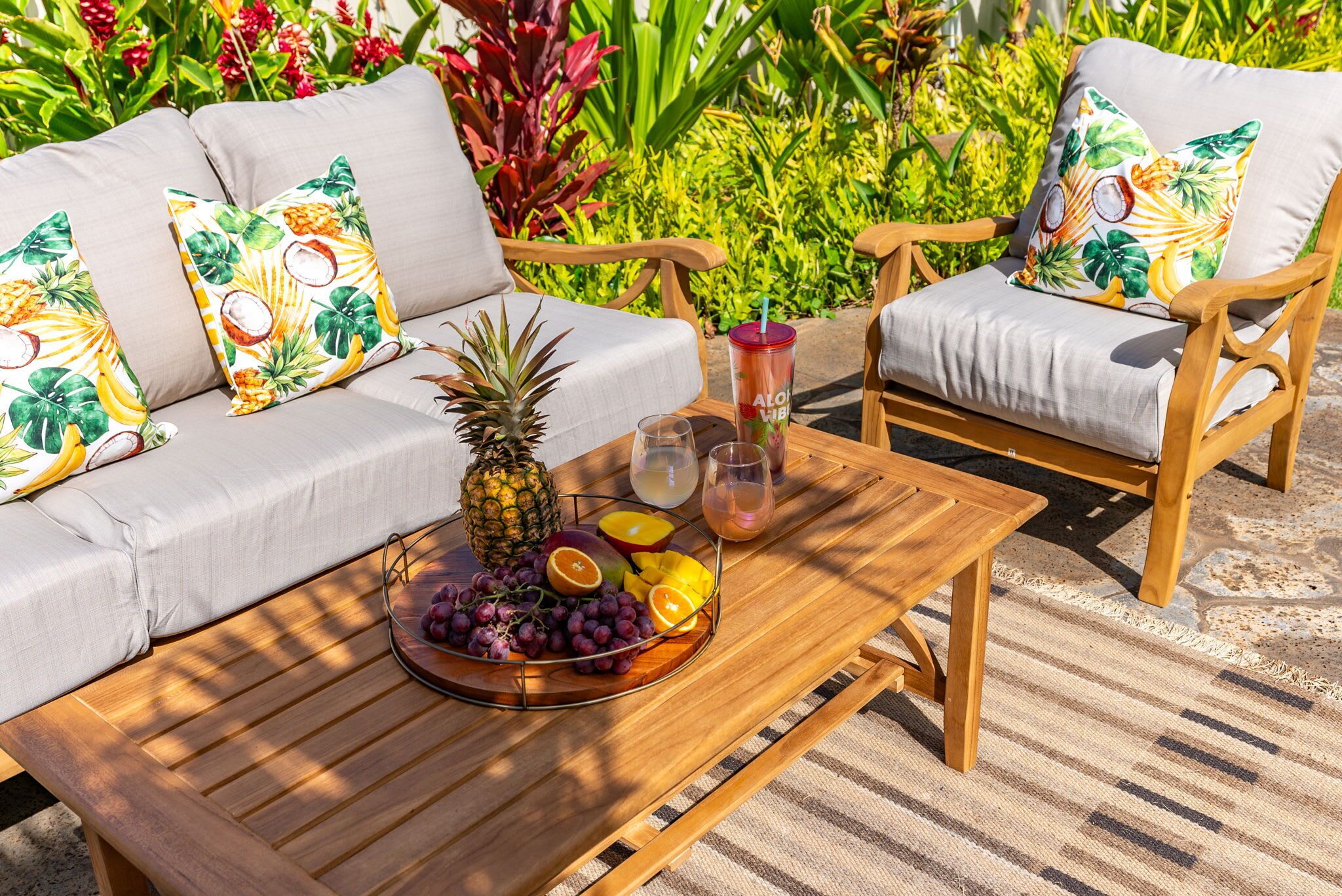 Una mesa de madera con un frutero, una bebida y un vaso.