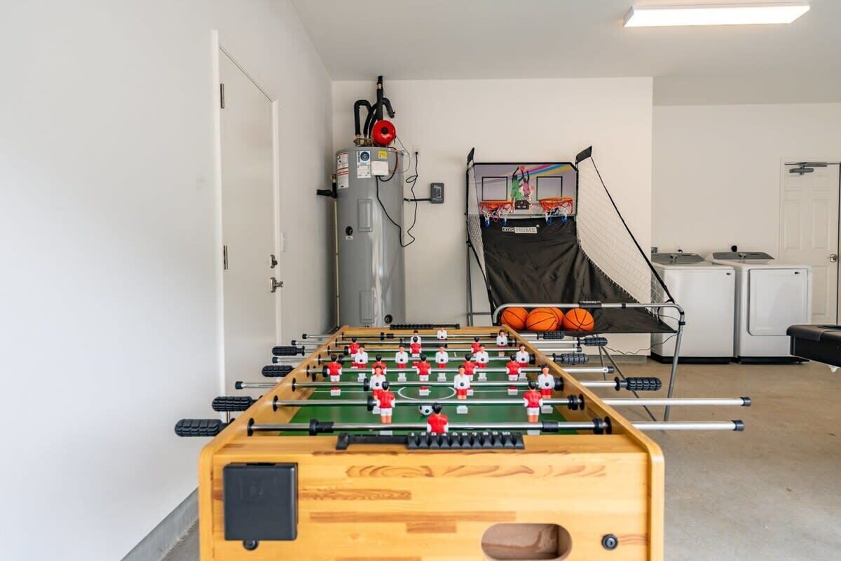 A room with a foosball table, a water heater, and a basketball hoop.
