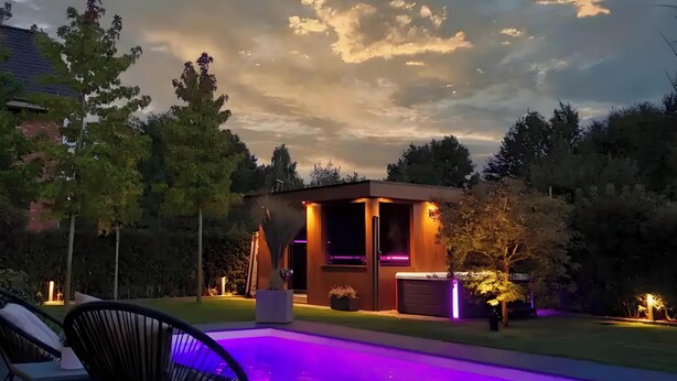 A modern house with a pool, surrounded by trees and a cloudy sky. - Luxurious 'Schaffner' Apartment with Private Pool, Sauna, Hot Tub, Terrace & Wi-Fi (Warendorf)