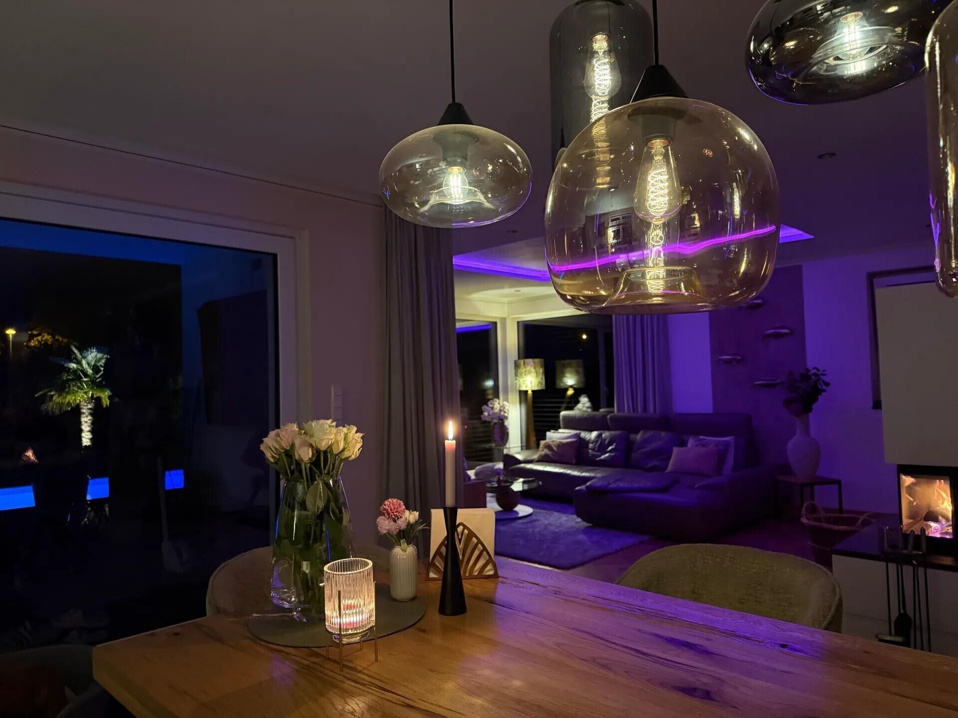 Un salon moderne avec une table à manger en bois, un canapé et des luminaires suspendus.