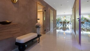 A modern lobby with a bench, a wall-mounted light fixture, and a glass door leading to a dining area. - Luxurious 'Schaffner' Apartment with Private Pool, Sauna, Hot Tub, Terrace & Wi-Fi (Warendorf)