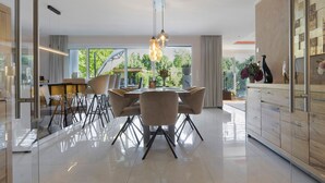 A modern dining area with a round table, chairs, and pendant lighting. - Luxurious 'Schaffner' Apartment with Private Pool, Sauna, Hot Tub, Terrace & Wi-Fi (Warendorf)