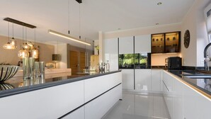 A modern kitchen with a central island, pendant lighting, and a view of the outdoors. - Luxurious 'Schaffner' Apartment with Private Pool, Sauna, Hot Tub, Terrace & Wi-Fi (Warendorf)
