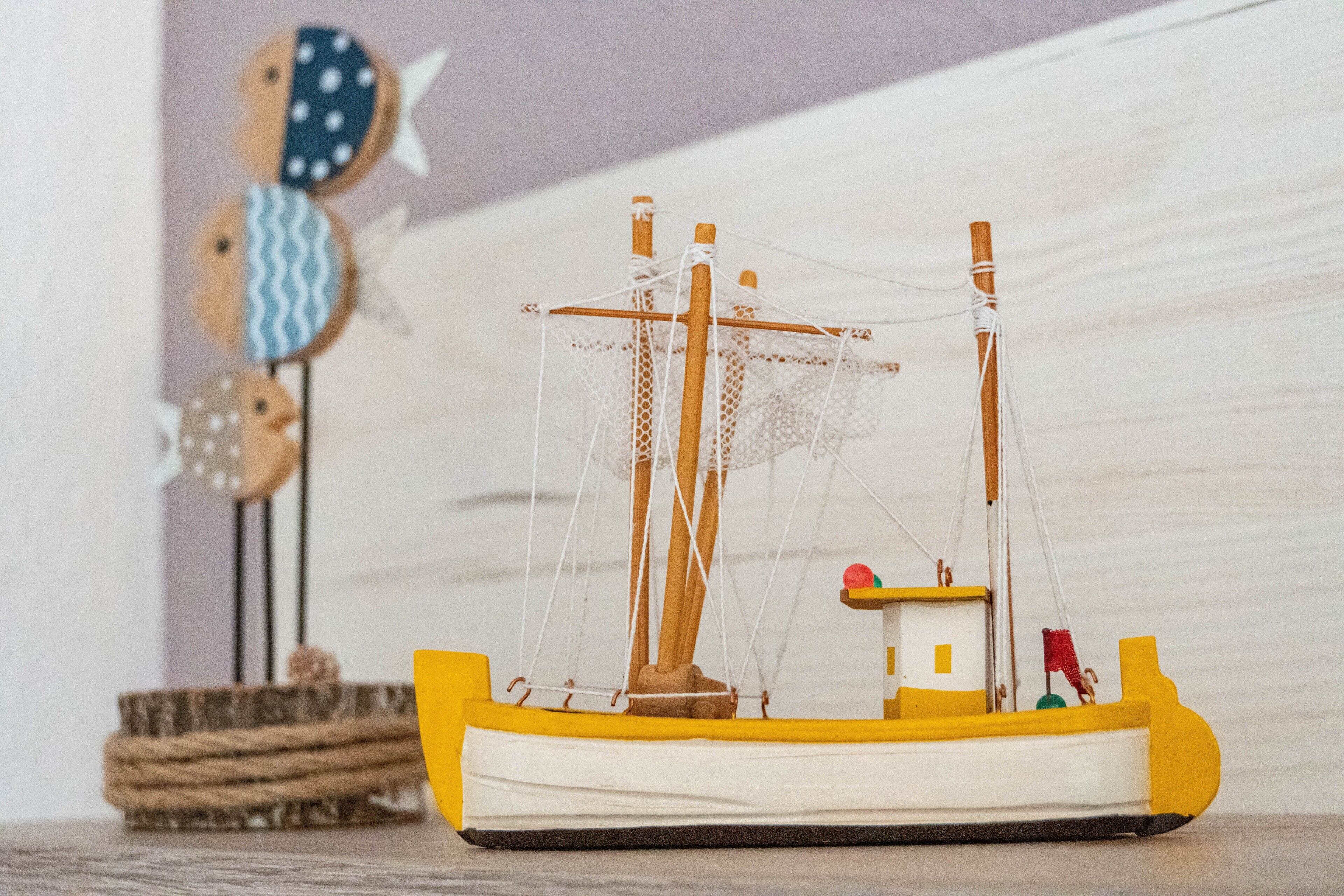 A model ship with a yellow hull and white deck, a small cabin, and a net.