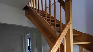 Un escalier en colimaçon en bois, doté d’une main courante et d’une balustrade ouverte, menant à l’étage supérieur.