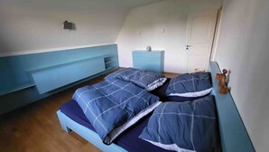 Une chambre à coucher avec un lit, une table de chevet, une commode et une porte.