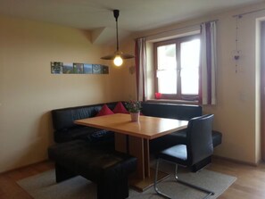 Un espace repas comprenant une table en bois, un canapé en cuir noir et un luminaire suspendu.