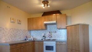 A kitchen with wooden cabinets, a stove, and a tiled backsplash.