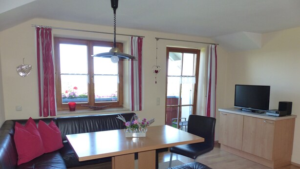 A living room with a sofa, a table, a bench, a television, and a window with curtains.