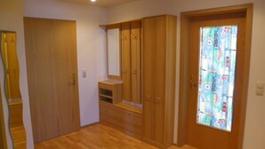 A room with wooden flooring, a mirror, a wardrobe, and a door with a colorful curtain.