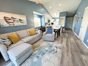 A living room with a sofa, armchair, and a rug. There is a kitchen in the background with a dining area. - NO STEPS #6 Lakeview Top Floor Blue Sky Escape (Branson)