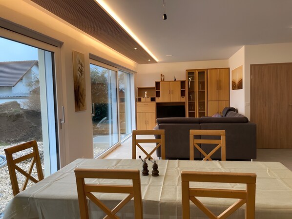 A modern living room with a sofa, wooden cabinets, and a dining table with chairs.