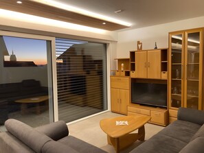A modern living room with a sofa, a small table, a TV, and a cabinet.