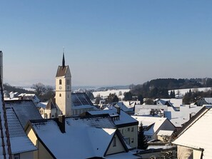 A town with snow-covered rooftops and a prominent church tower.
