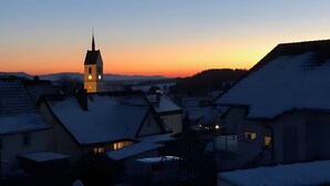 A town with snow-covered rooftops and a church with a clock tower. - Single Room with Wi-Fi (Wäschenbeuren)
