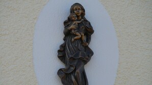 A wall-mounted sculpture of a figure holding a child, with a textured wall background. - Single Room with Wi-Fi (Wäschenbeuren)