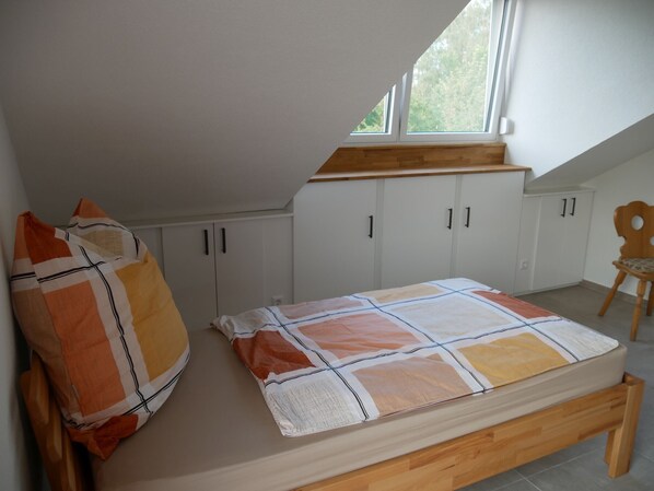 A bedroom with a bed, a window, and white cabinets.