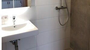 A bathroom with a white sink, a mirror, and a shower with a handheld showerhead. - Single Room with Wi-Fi (Wäschenbeuren)