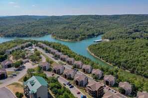 A residential area with houses along a river, surrounded by forest.