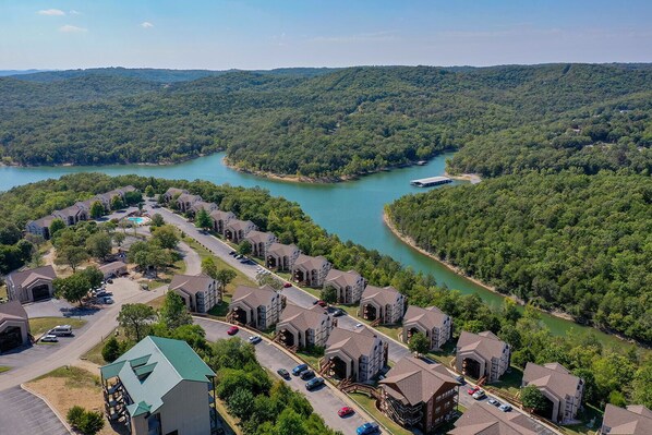 A residential area with houses along a river, surrounded by forest.