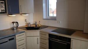 A modern kitchen with a dishwasher, oven, sink, and a Siemens coffee maker.