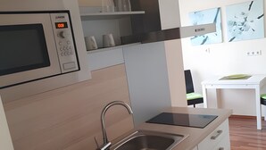 Una cocina moderna con microondas, lavamanos y un comedor con una mesa y sillas blancas.