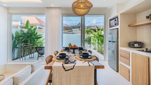 A modern kitchen with a dining area, large windows, and a view of the outside. - Villa Balinay (Canggu)