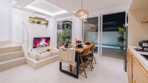 A modern living room with a dining area, a staircase, and a kitchen. - Villa Balinay (Canggu)