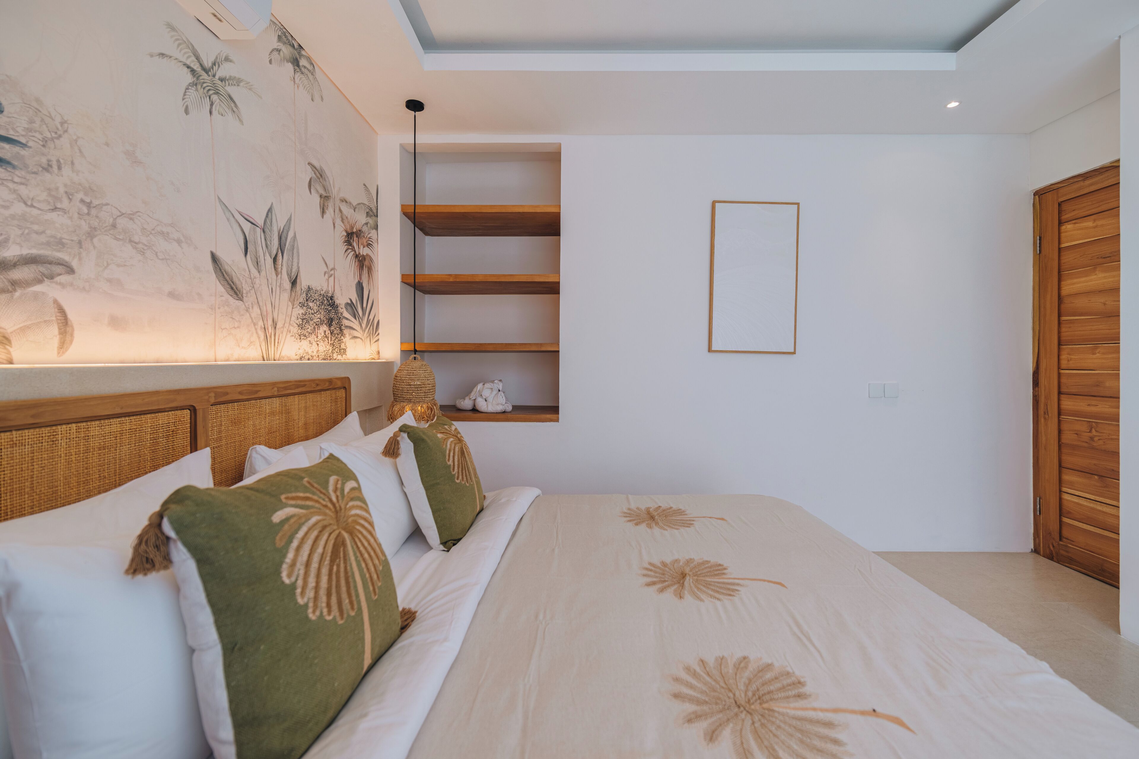 A bedroom with a large bed, a wall-mounted shelf, and a ceiling light.