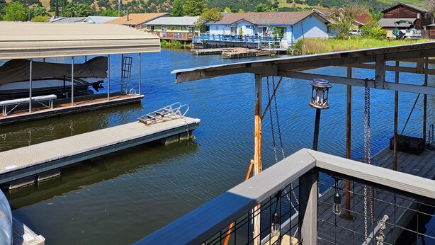 A marina with docked boats, a covered boat launch, and a view of the surrounding hills and buildings.