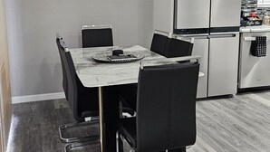 A dining area with a marble table, black chairs, and a framed quote on the wall.