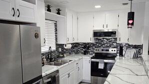 A modern kitchen with stainless steel appliances, white cabinetry, and a black and white backsplash.