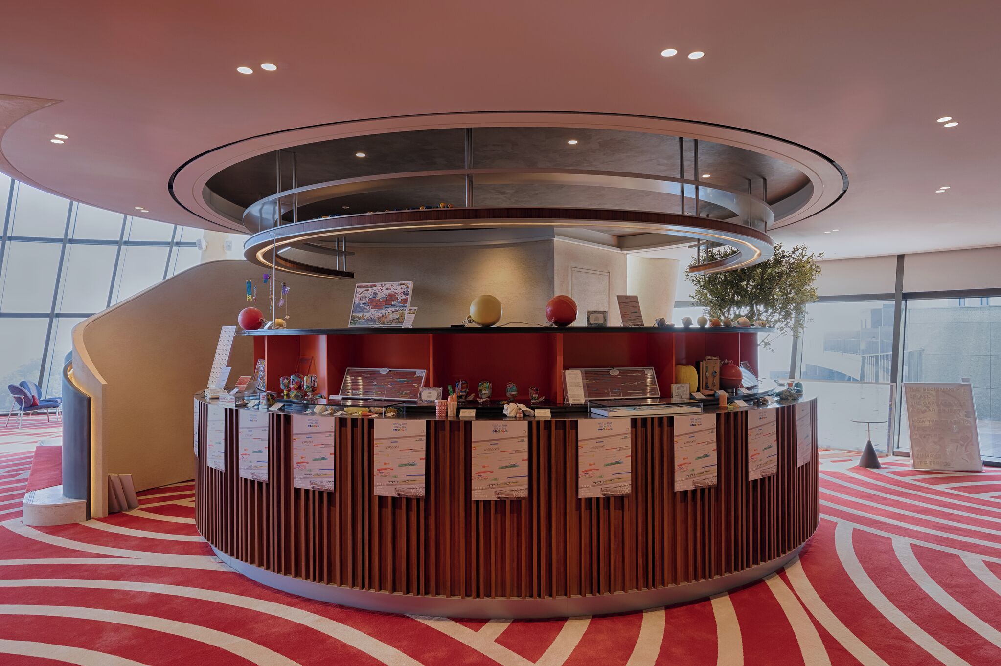 A modern reception desk with a circular design, surrounded by a red carpeted area.