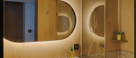 A modern bathroom with a large mirror, a sink, and a shower area.